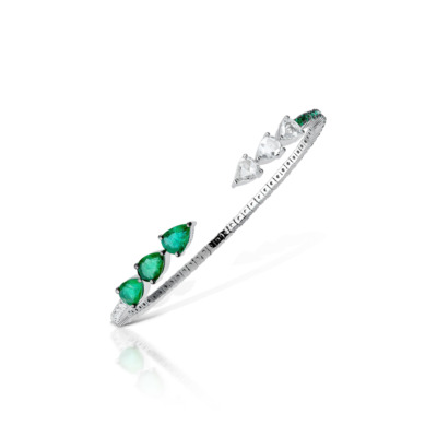 Silver bangle featuring pear-shaped emeralds and diamonds arranged in a linear pattern.