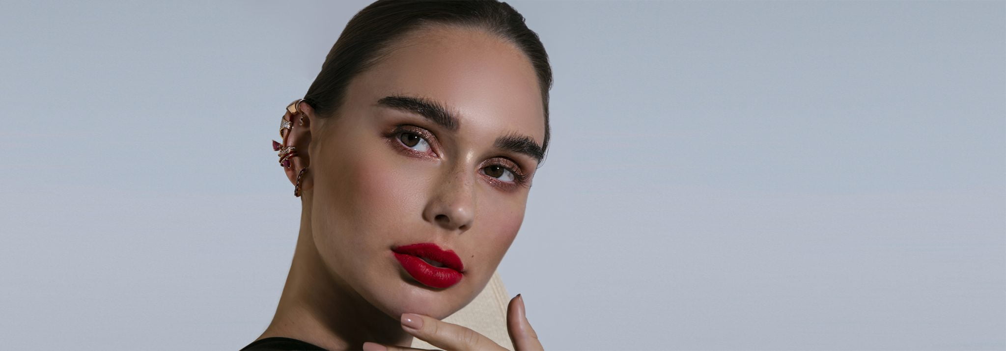 Close-up of a model showcasing bold red lips and stylish ear jewelry, highlighting beauty and fashion trends.