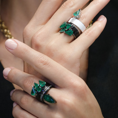 Multiple rings featuring green gemstones worn on fingers, showcasing various designs and styles.