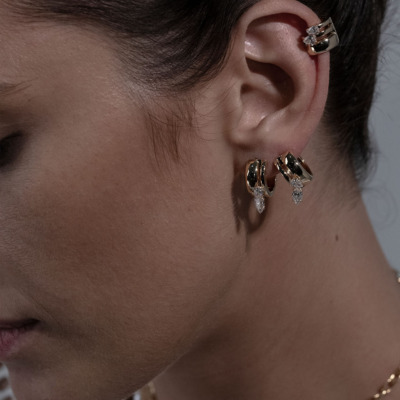 Close-up of a model wearing elegant gold earrings with diamond accents, showcasing a modern design and sophisticated style.
