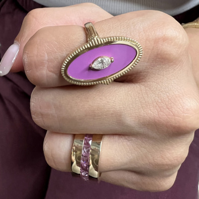 Gold ring featuring a large purple stone and a diamond accent on a person's hand.