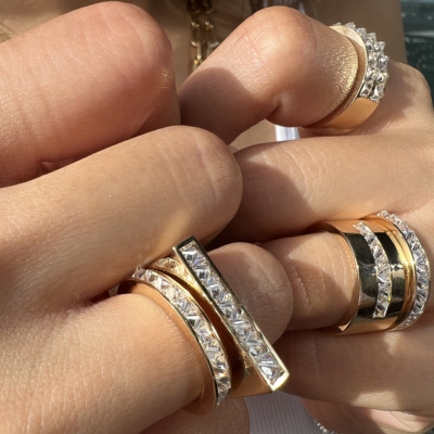 Multiple rings featuring gold and silver bands with clear stones displayed on fingers.