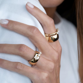 Two gold rings with a diamond accent worn on a hand with a neutral manicure.