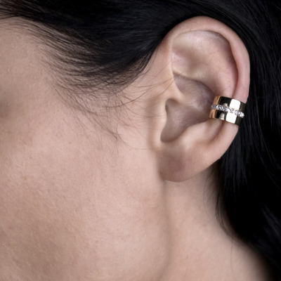 Close-up of a person's ear featuring a gold and silver ear cuff accessory.