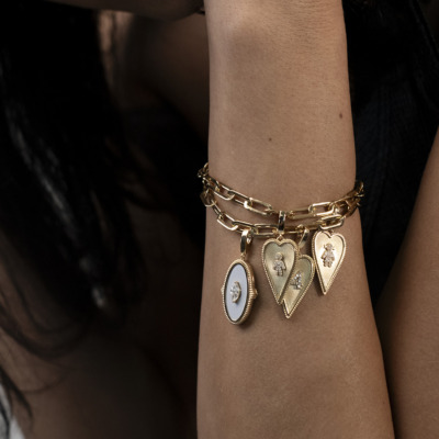 Gold bracelet featuring multiple heart-shaped lockets and a round locket with a white center.