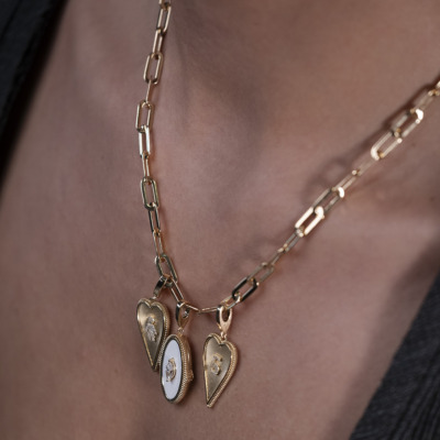 Gold necklace featuring three heart-shaped pendants with intricate designs hanging from a chain.