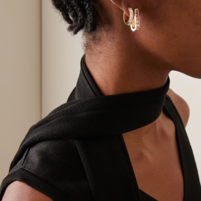 Close-up of a person wearing 18K yellow gold diamond hoop earrings in their ear.