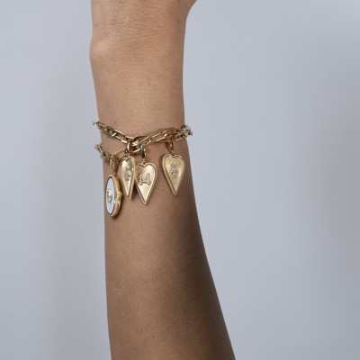 Gold charm bracelet featuring multiple pendants on a wrist.