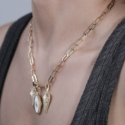 Gold chain necklace featuring two heart-shaped pendants with intricate designs.