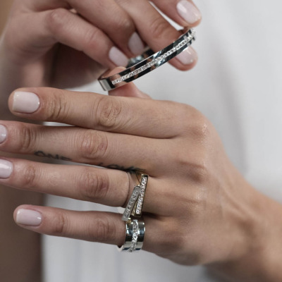 Close-up of hands wearing multiple silver and gold rings and bracelets with decorative elements.