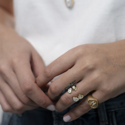 Close-up of a hand wearing multiple rings, including gold and silver designs with gemstones.