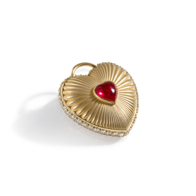 Gold heart-shaped locket featuring a red gemstone at the center and a decorative design.