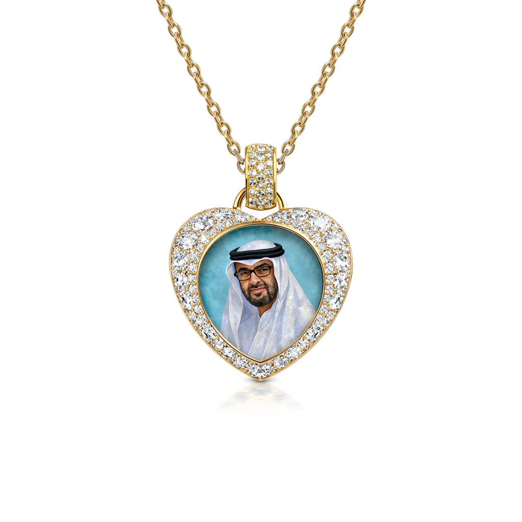 Heart of the Nation pendant in 18k gold with a diamond pavé halo around a portrait of Sheikh Mohamed bin Zayed Al Nahyan, blue backdrop