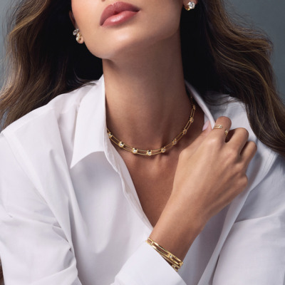 Savolinna gold Forme Beam Cuff Slim Model featuring diamond accents, complemented by a matching necklace and earrings on a model in a white shirt