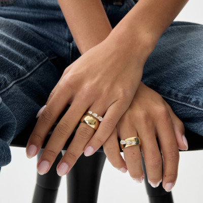 Savolinna gold rings with diamonds on hands, close-up with denim background and manicured nails, highlighting elegant jewelry pieces